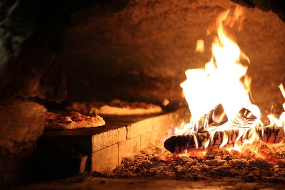 Rustic oven with pizzas near vibrant flames