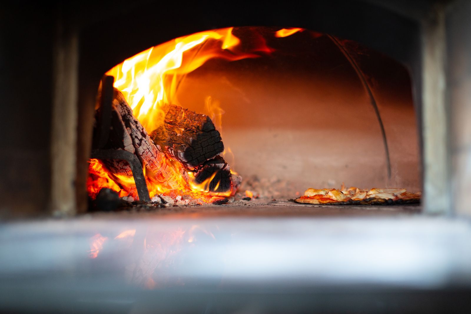 Wood-fired oven flames near pizza