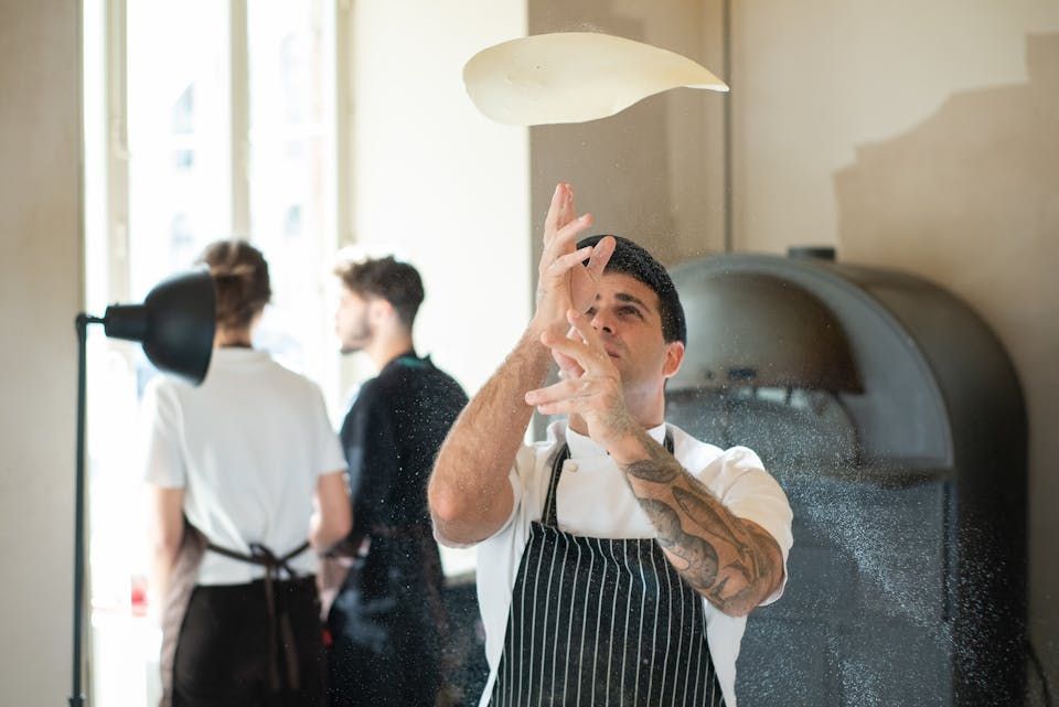 Chef tossing pizza dough in a pizzeria kitchen